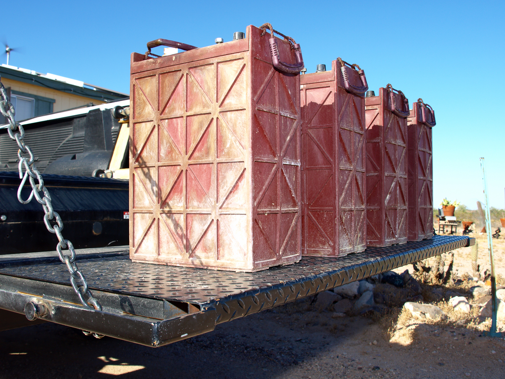 Four large wet cell lead acid batteries loaded onto a truck liftgate