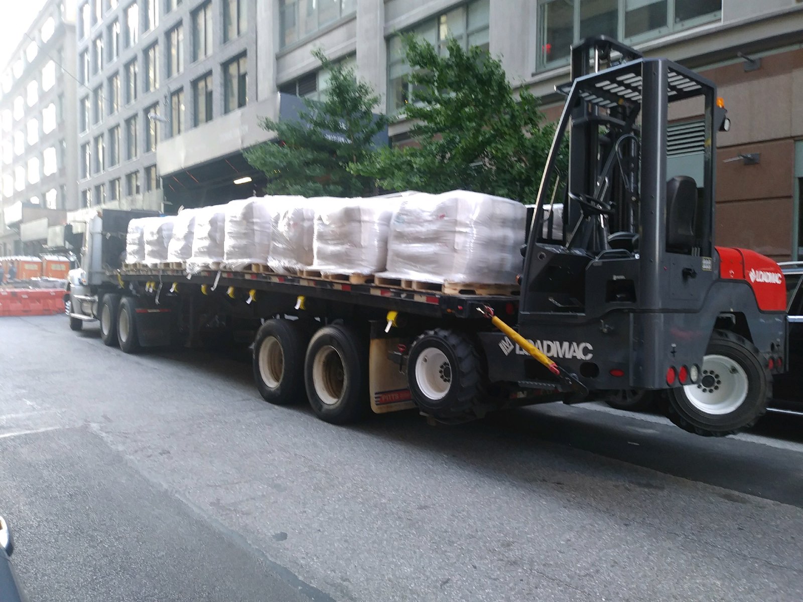 Flatbed truck hauling materials with a forklift on the back