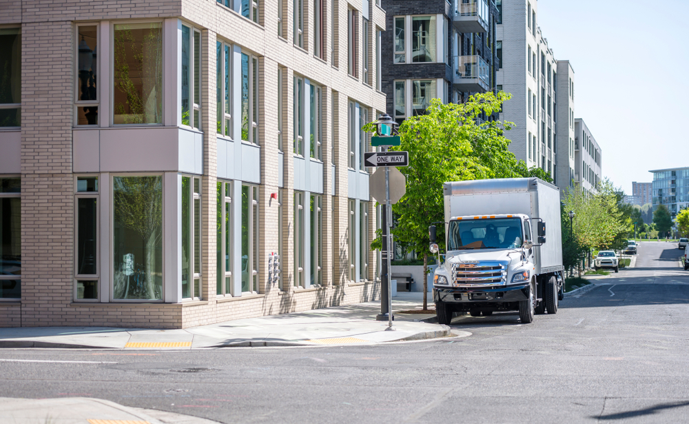 truck with box trailer for local deliveries standing on the city street with multilevel apartment buildings